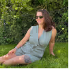 WPF Community - Eine lächelnde Frau mit Sonnenbrille und hellem Jumpsuit sitzt im Gras.