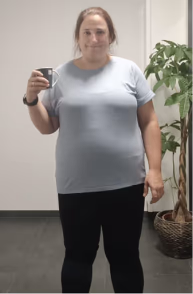 Eine lächelnde Frau in Jeans und T-Shirt hält eine Tasse in der Hand.