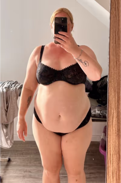 Eine Frau in schwarzer Unterwäsche macht ein Selfie im Spiegel.